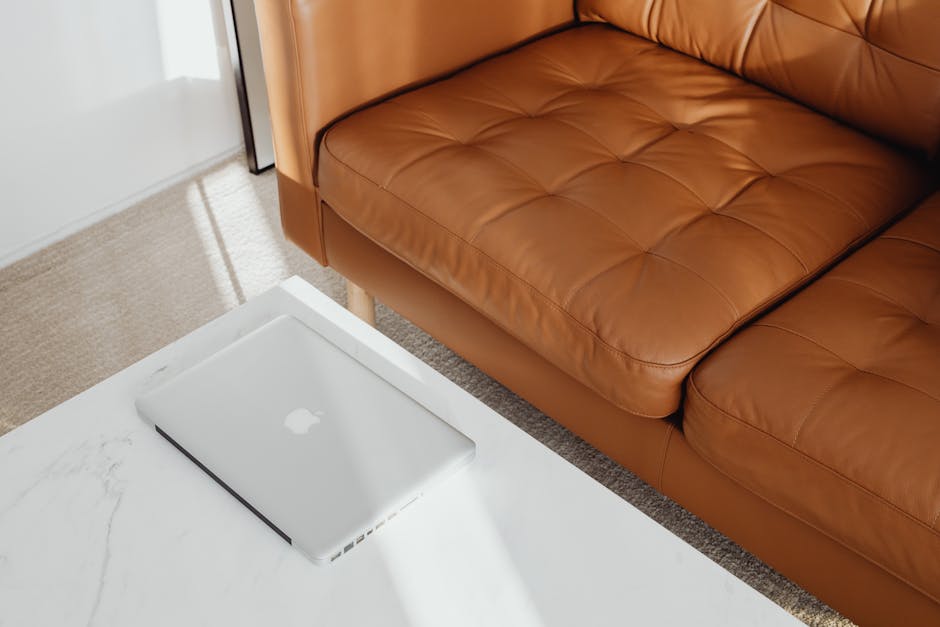Stylish living room featuring a brown leather couch and laptop on a marble table.